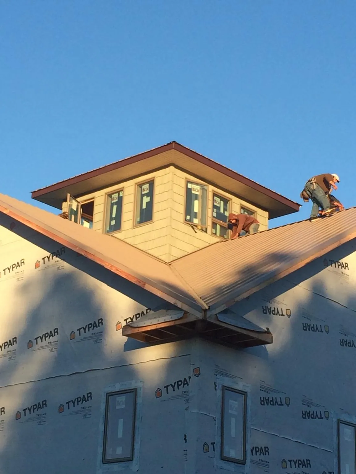 Roofers working around a rooftop cupola on a new metal roof at sunset — Roof Waterproofing in Greensburg by Roofing Brothers